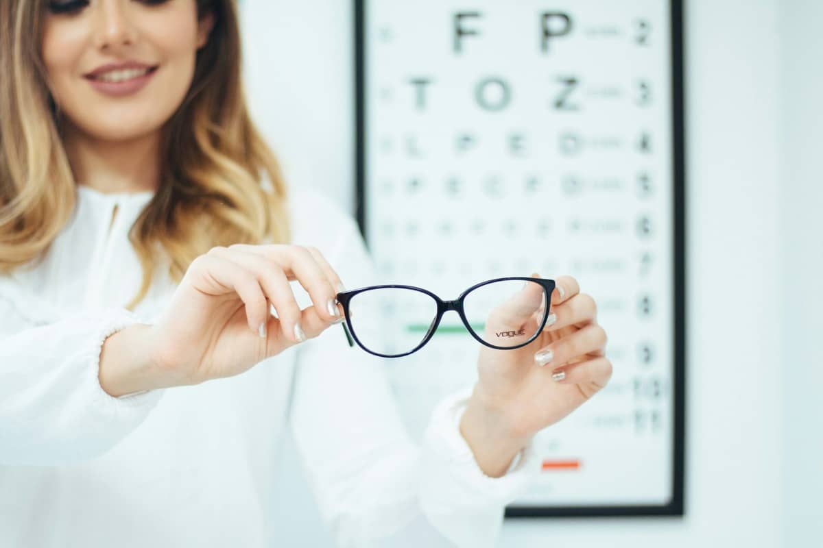 A home-visit optician carrying out an eye test for an older man in his living room