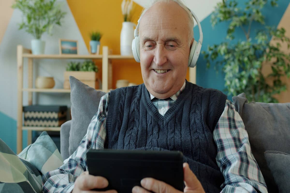 An audiologist carrying out a home hearing test with an older man in his living room